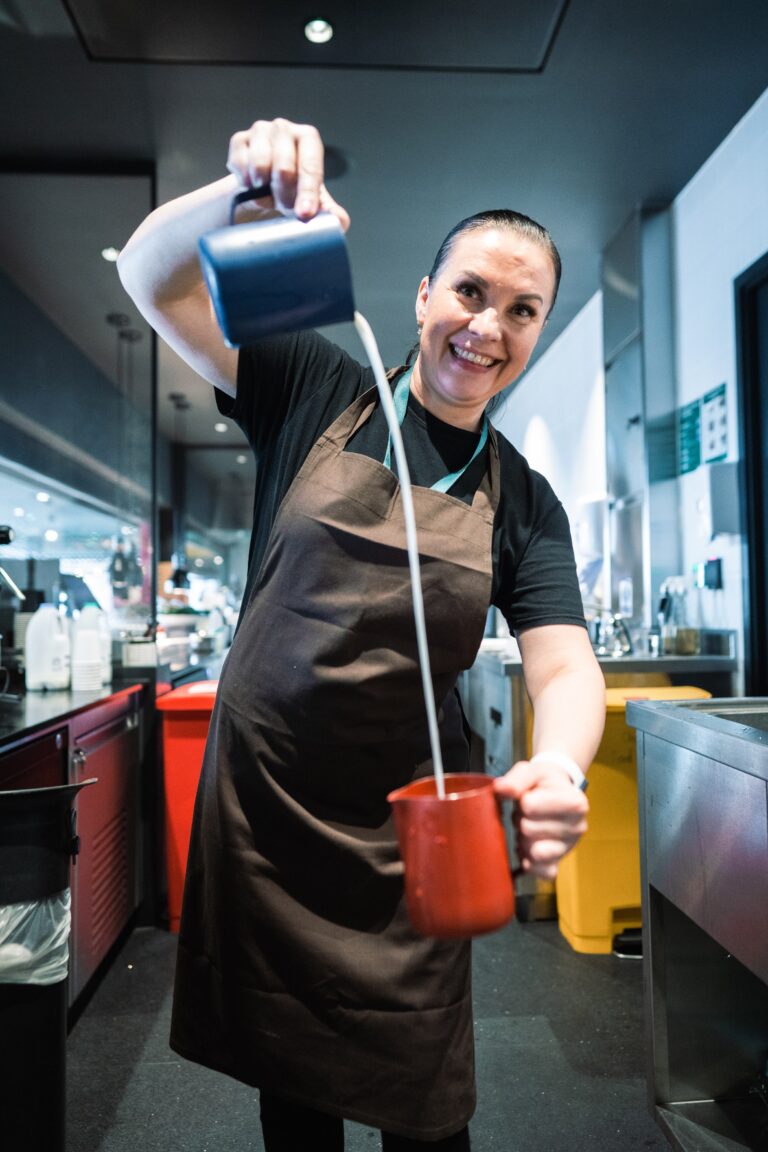 Barista making coffee pouring milk